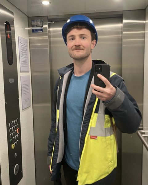 Robin en casque et gilet de chantier, en visite sur un chantier